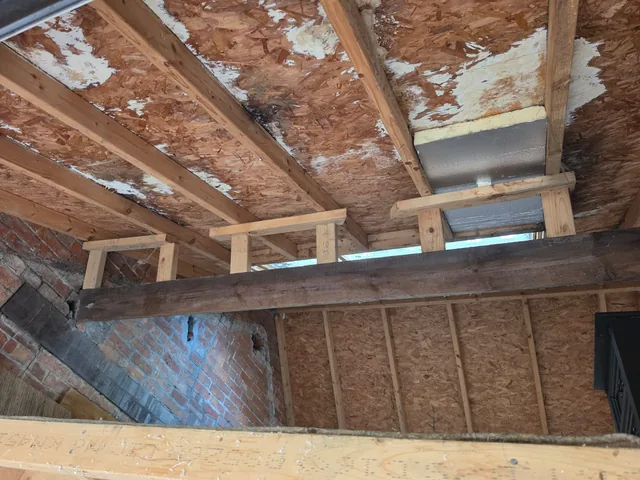 Timber supports and a dark beam sit beneath worn garage roof boards.