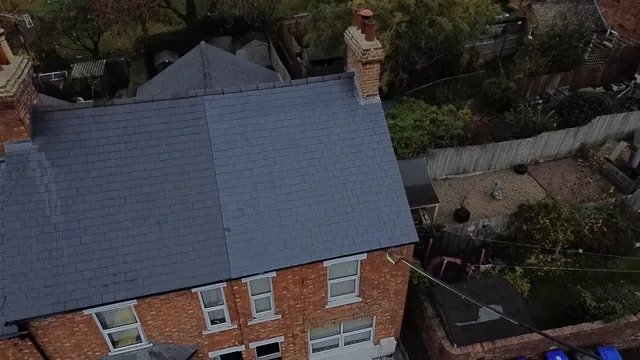 An aerial view shows grey slate courses above red brick walls and white windows.